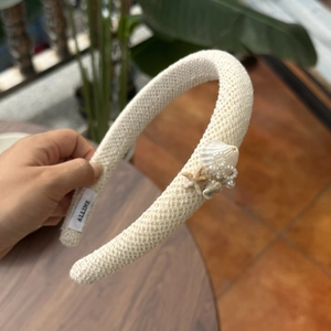 Close-up of beige woven headband with seashell, starfish decorations and faux pearls