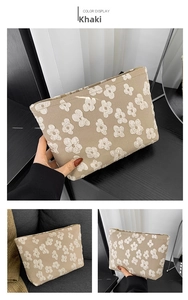 Detail of khaki fabric pouch with white embossed floral patterns and zipper closure