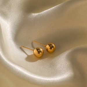 Macro shot of minimalist 18K gold plated stainless steel ball stud earrings on silk