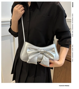 Close-up of a silver bow handbag with metallic finish and thin shoulder strap detail