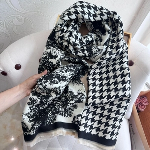 Detailed close-up of houndstooth cashmere feel scarf with fringe on a white chair