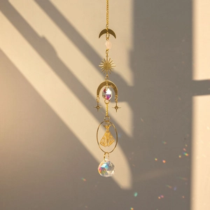 Detail of brass suncatcher with crystals casting rainbow light on a soft wall