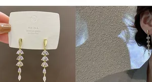 Close-up of long gold tassel earrings with teardrop zircons and 925 silver needles