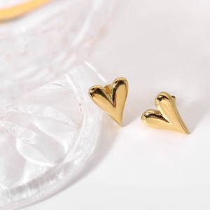 Detailed view of 18K gold plated heart stud earrings on decorative glass accessory