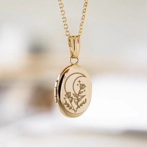 Oval gold locket necklace with moon and floral engraving on a classic cable chain