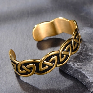 Vintage gold stainless steel Viking Celtic knot open cuff bracelet on dark stone surface
