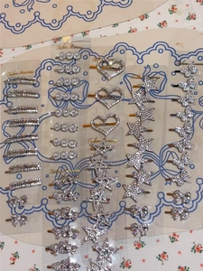 Detail of assorted Y2K metal hair clips with rhinestones and pearls on floral background