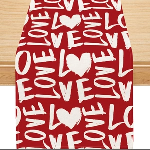 Red Valentine's table runner with LOVE and heart patterns on light wood surface