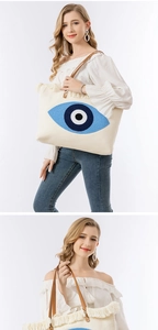 Detail of bohemian canvas tote with embroidered evil eye motif and fringe trim detail