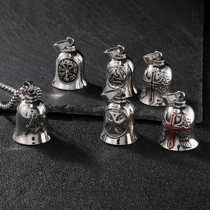 Detailed view of silver Viking and Masonic steel motorcycle bells on dark stone surface