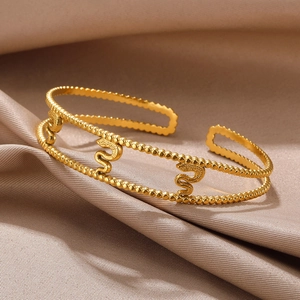 Detail of gold-plated stainless steel open bangle featuring snake links and beaded edges