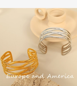 Detail of multi-layer wavy gold and silver steel bangles with open cuff design