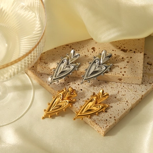 Detail of layered gold and silver heart earrings with beaded edges on a stone display