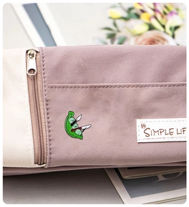 Détail du pin's émaillé cosse de pois vert avec couteau sur un sac en toile blanc
