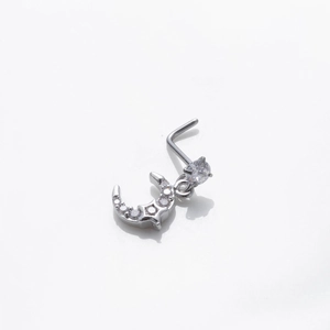 Détail macro du piercing nez en L argenté avec pendentifs lune et étoile en zircon