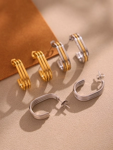 Macro detail of multi-layer gold and silver C-shaped hoop earrings on elegant textured background