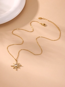 Gros plan d'un collier pendentif étoile à huit branches dorée avec oxydes de zirconium