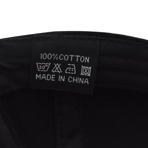 Detail shot of the 100% cotton wash label and care instructions inside the black cap