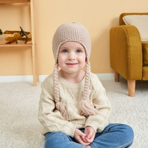 Close-up of a knit baby earflap hat with decorative braided tassels and soft lining