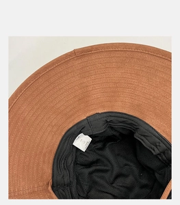 Close-up of brown sun hat with black mesh lining and sizing label showing fine stitching