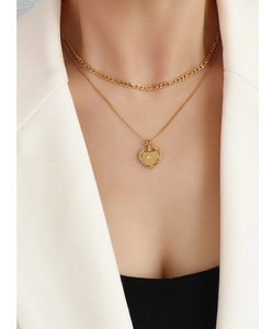 Détail d'un collier double épaisseur doré avec maille Figaro et pendentif cœur gravé