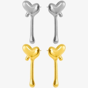 Detail view of heart-shaped tassel earrings in gold and silver finish on white background