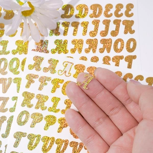 Close-up of 0.5 inch gold glitter alphabet stickers for spice jars and balloon decor