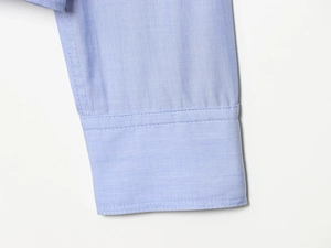 Detailed macro view of the light blue woven shirt cuffs and precision stitching