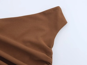 Détail du tissu froncé marron sur le haut asymétrique et la jupe midi texturée
