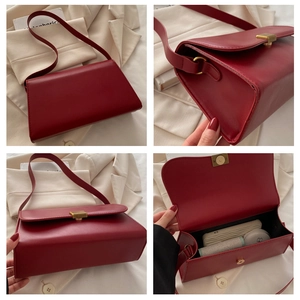 Detail view of red leather crossbody bag with gold buckle and internal storage capacity