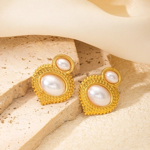 Detailed close-up of vintage gold floral earrings with pearls on cream silk and stone