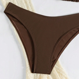Vue détaillée du bas de bikini marron foncé avec coutures de qualité sur dentelle blanche