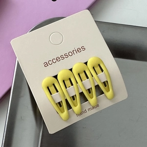 Detail shot of four yellow drop-shaped matte hair clips on white card for girls