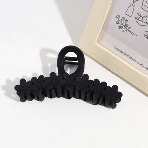 Detail shot of a matte black 13cm flower hair claw clip on a minimalist white background