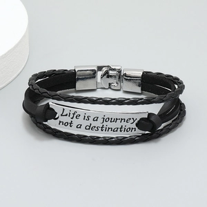 Macro detail of leather braided bracelet with engraved silver plate Life is a journey