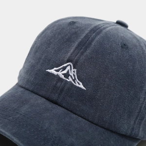 Macro detail of mountain embroidery on washed navy cotton baseball cap fabric