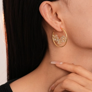 Créoles dorées avec fleurs en zircon étincelant portées par un mannequin look de luxe