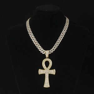 Détail d'une chaîne cubaine hip hop dorée avec pendentif croix Ankh pavé de diamants