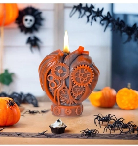 Mechanical heart candle with gears lit in a spooky Halloween setting with pumpkins