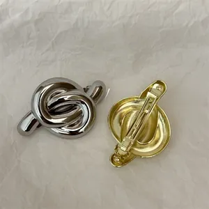 Detailed close-up of gold and silver knot hair clips with metallic spring mechanism