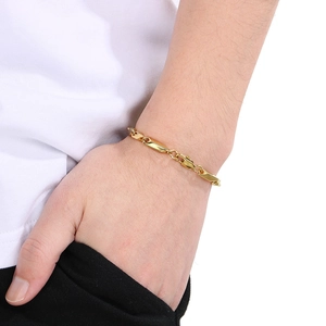 Détail d'un bracelet gourmette en acier inoxydable doré porté au poignet d'une femme
