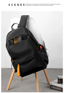 Detail of waterproof black nylon backpack with vibrant orange zipper pulls and side pocket