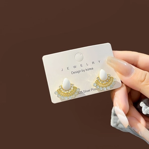 Detail of elegant gold fan-shaped stud earrings with teardrop pearls and 925 silver post