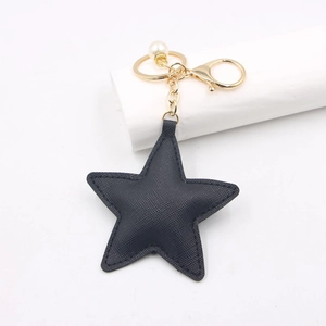 Detailed view of a black star PU leather keychain with gold hardware and pearl bead