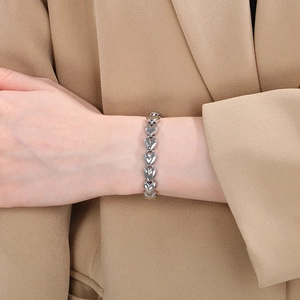 Detailed close-up of a silver heart-link titanium steel bracelet on a woman's wrist