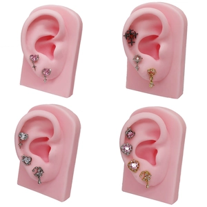 Set of heart, cross and floral heart cartilage studs with zircons on pink ear model