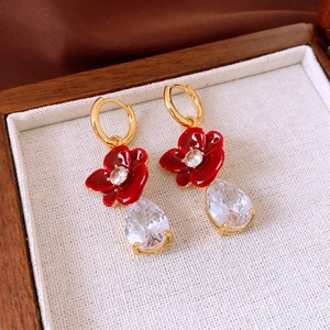 Detailed close-up of 18k gold flower earrings with red petals and zircon drop pendants