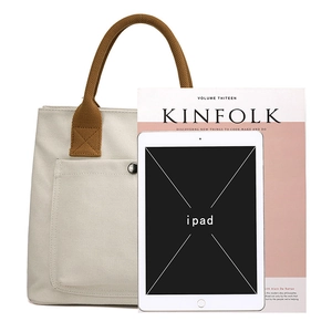 Canvas tote bag with brown handles and front pocket, casual daily handbag for women.
