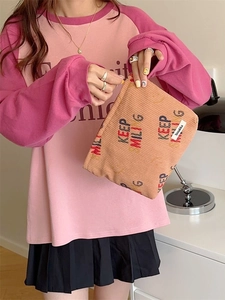 Pink corduroy makeup bag with Keep Smiling print and zipper closure held by hand