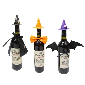 Trio of mini witch hats and capes decorating wine bottles for Halloween party setup